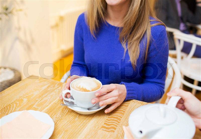 People, leisure and drink concept - close up of woman with coffee cup at cafe, stock photo