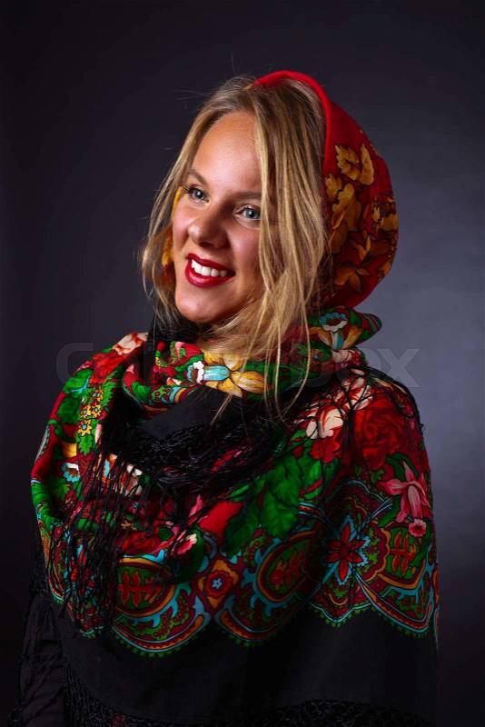 Beautiful young woman in a red traditional Russian shawl on black background, stock photo