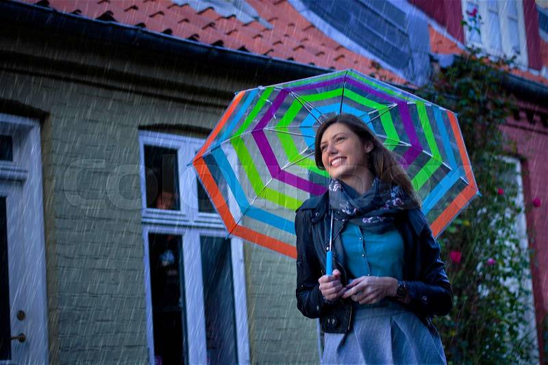Smiling beautiful girl with her umbrella on a rainy day. Smiling beautiful girl with her umbrella on a grey day. Standing in a cute traditional scandinavian street, stock photo