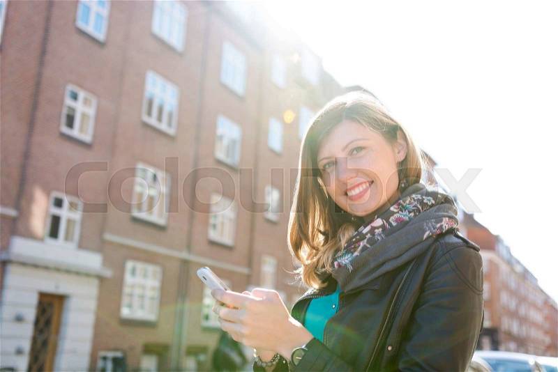 Charming sweet caucasian girl with her phone in the urban life, stock photo