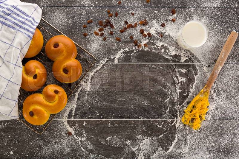 Baking of swedish Saffron buns, buns on cooling rack on floury table. with milk and fork with yelllow dough, stock photo