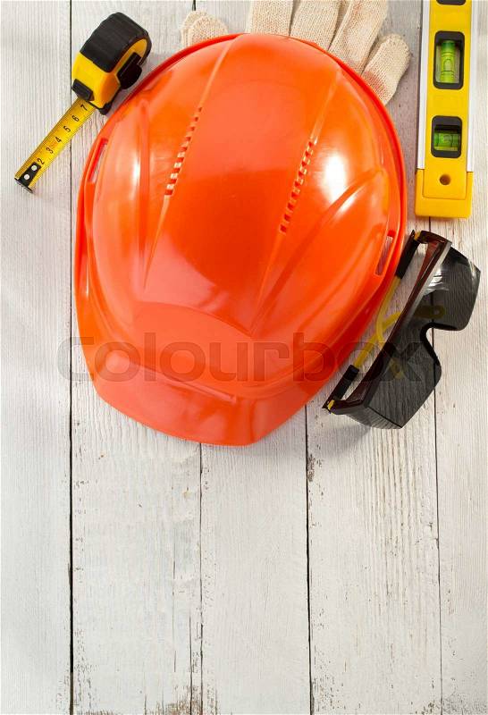 Hardhat and safety glasses on wooden background, stock photo