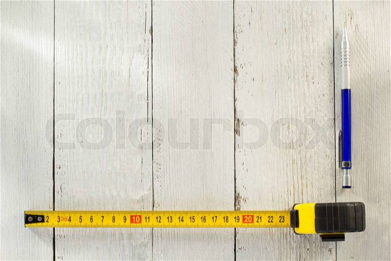 Tape measure and pencil on wooden texture, stock photo