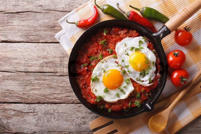 Mexican fried eggs huevos rancheros close-up in a frying pan on the table. horizontal view from above , stock photo