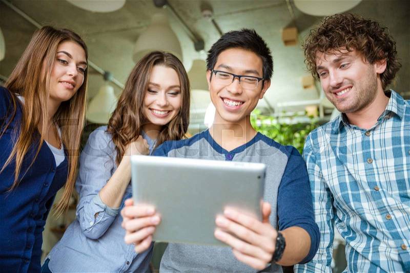 Happy positive attractive people looking on the screen of tablet and smiling, stock photo