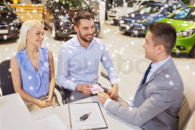 Auto business, sale and people concept - happy couple with dealer buying car in auto show or salon over snow effect, stock photo