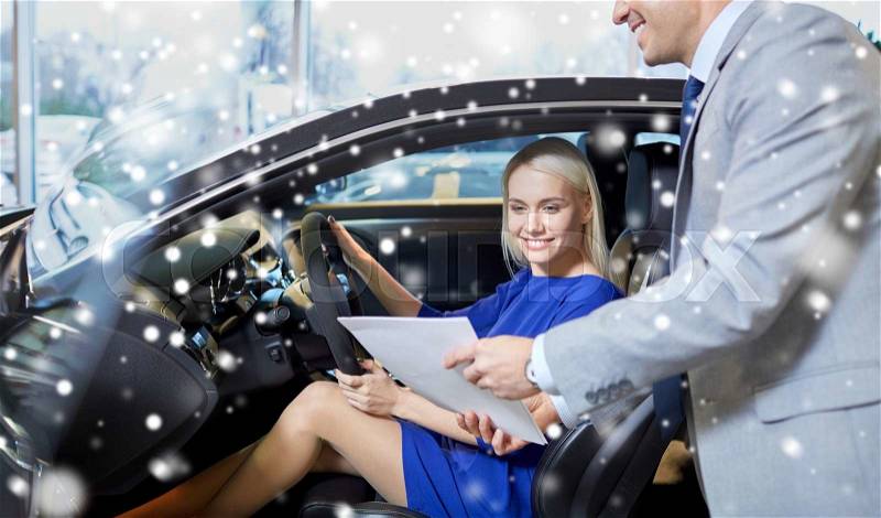 Auto business, car sale, consumerism and people concept - happy woman with car dealer in auto show or salon over snow effect, stock photo