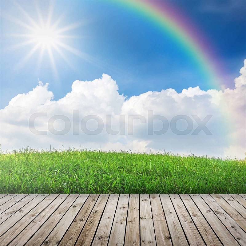 Green field under blue sky with sun beam. Wood floor, stock photo