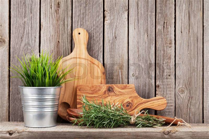Cooking wood utensils and herbs on shelf in front of wooden wall with copy space, stock photo