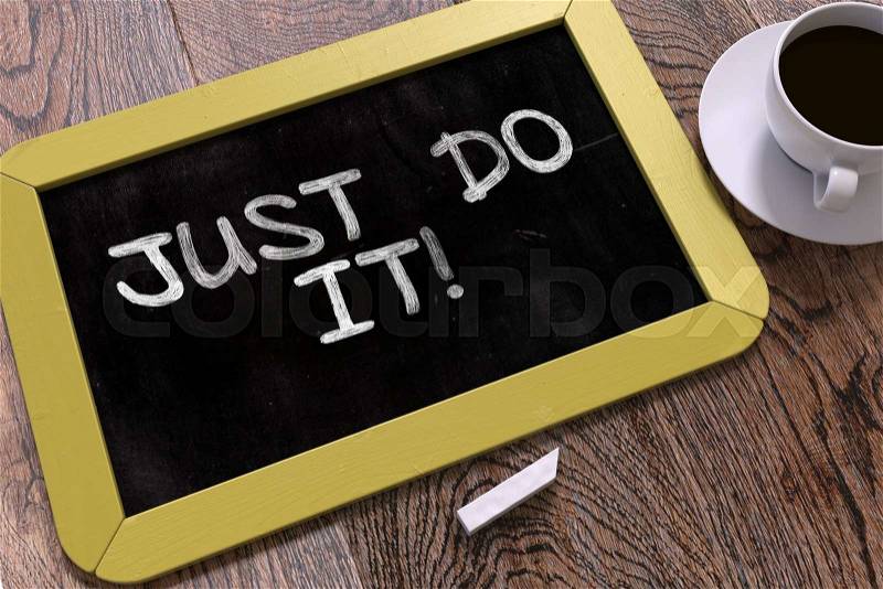 Just Do It. Motivational Quote Hand Drawn on Yellow Chalkboard on Wooden Table. Business Background. Top View, stock photo