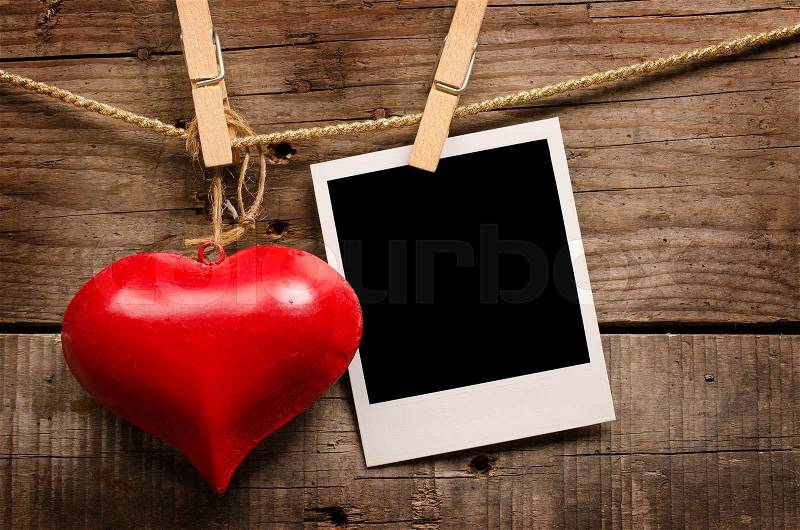Red heart shape and old photo on a wooden background, stock photo