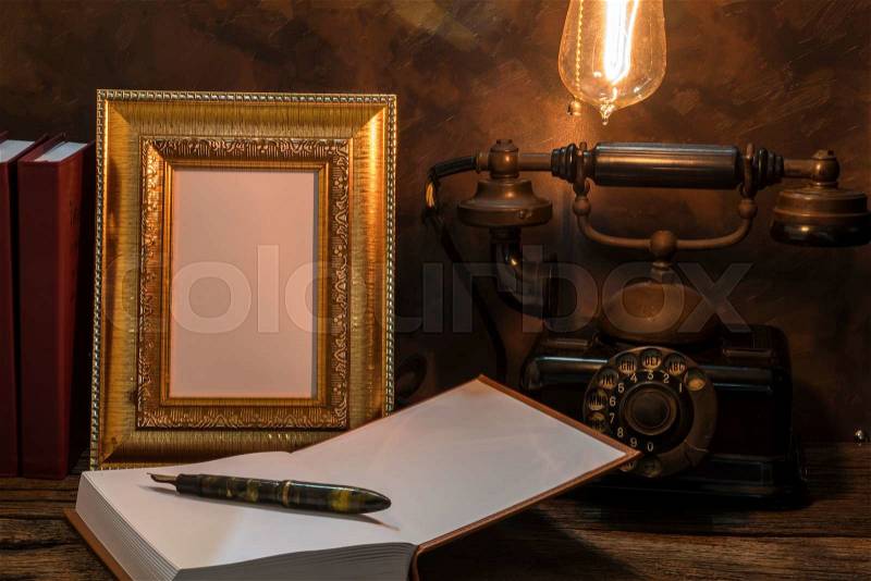 Still life of vintage telephone with picture frame and diary on table, stock photo