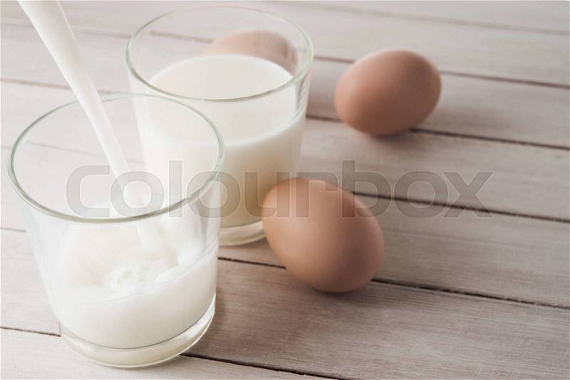 Glass with milk and eggs on table, stock photo