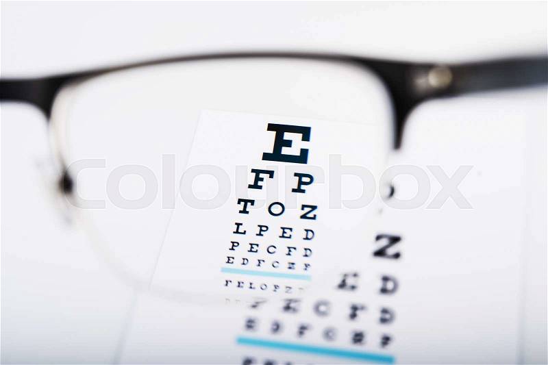 Eye glasses focus on exam chart on background, stock photo