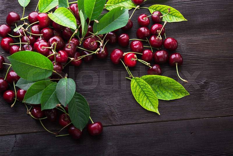Sweet ripe cherry with leaf on dark wood background, stock photo
