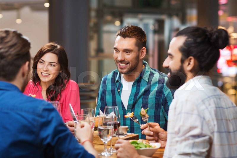 Leisure, food and drinks, people and holidays concept - happy friends having dinner at restaurant, stock photo