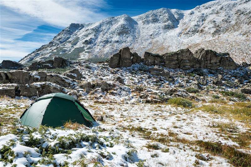 Green tent in snow mountains. Beautiful spring landscape, stock photo