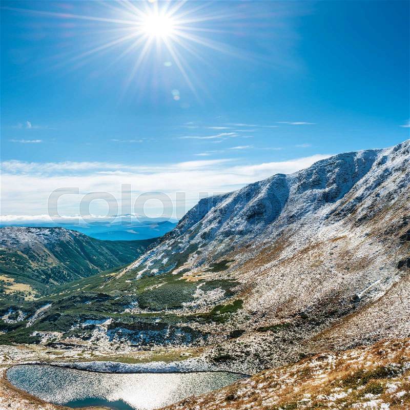 Beautiful lake in the winter mountains. Landscape with sun and snow, stock photo