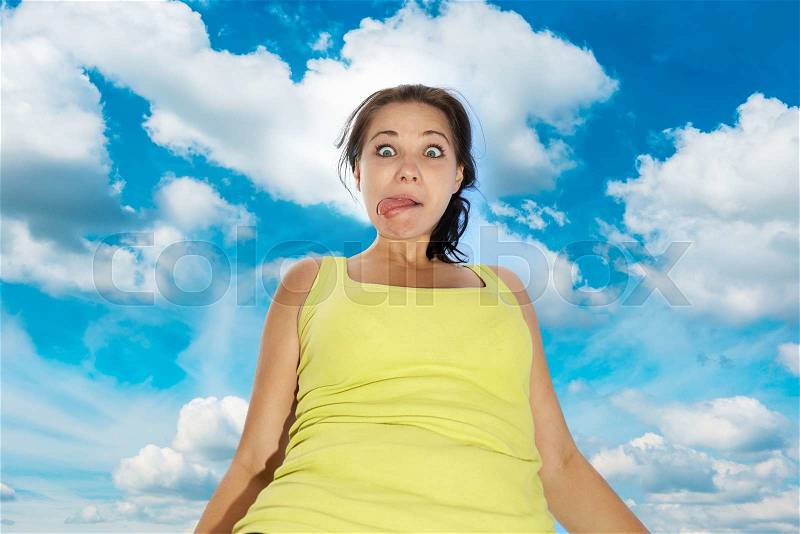 Pretty young girl with funny face expression over blue sky with clouds, stock photo