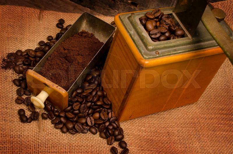 Old used coffee mill with coffee beans on a coffee bag, stock photo