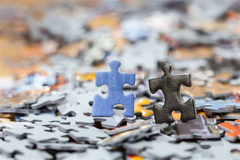 Black and blue puzzle pieces on a pile of jigsaw pieces. Shallow depth of field, stock photo