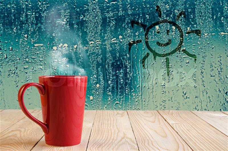 Red coffee cup with smoke and sun sign on water drops glass window background, stock photo