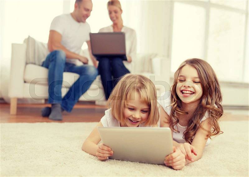 Family, children, technology and home concept - smiling sister with tablet pc computer and parents on the back with laptop, stock photo
