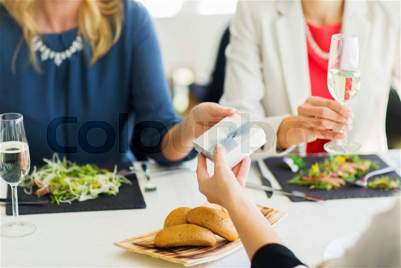 People, holidays, celebration and lifestyle concept - close up of women giving birthday present at restaurant, stock photo