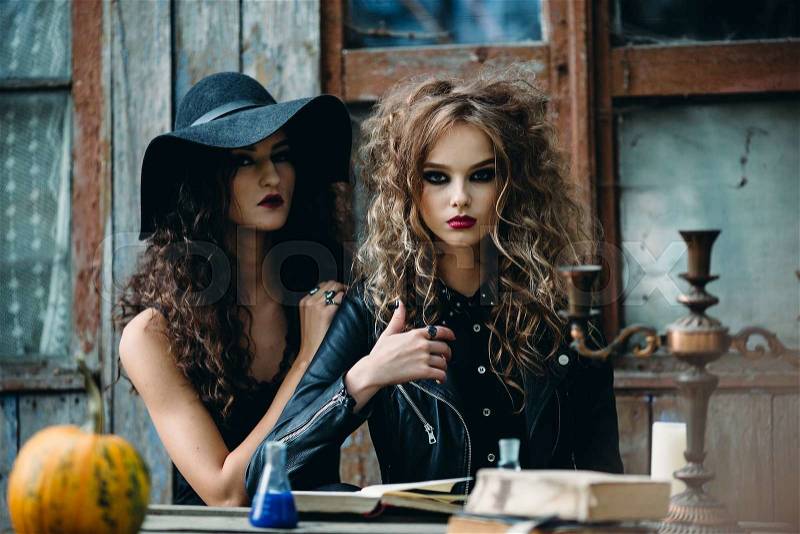 Two vintage witch sitting at the table in an abandoned place on the eve of Halloween, stock photo