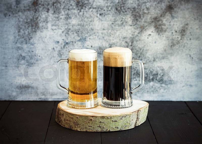 Light and dark beer in mugs on wooden board, grunge backdrop, stock photo