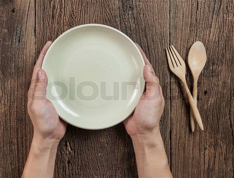Top view of hand hold a empty bowl with spoon on wood, stock photo