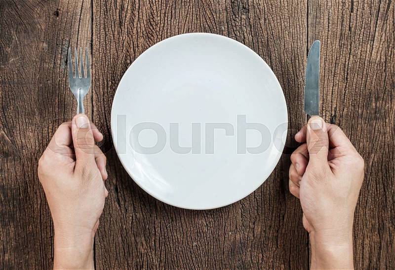 Hand hold fork and knife with plate on wood, stock photo