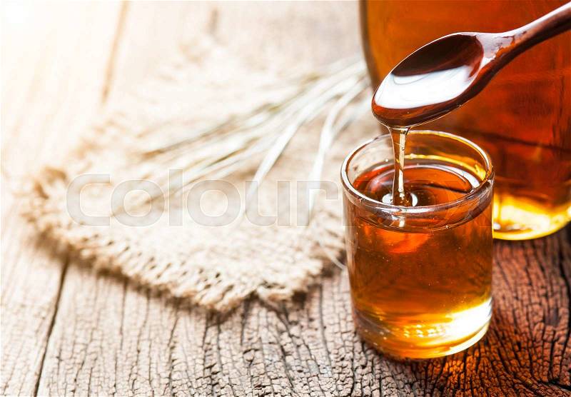 Maple syrup in glass bottle on wooden table, stock photo
