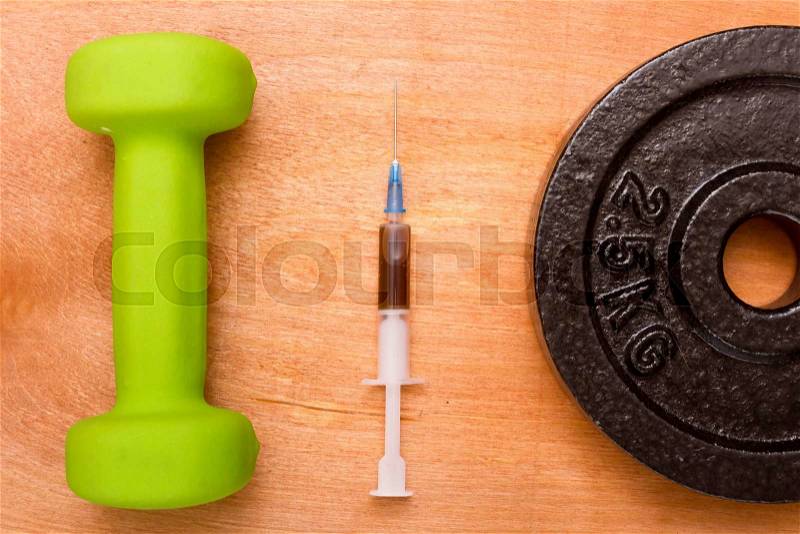 The syringe filled with doping between sports dumbbell and additional weight for the big dumbbells, stock photo