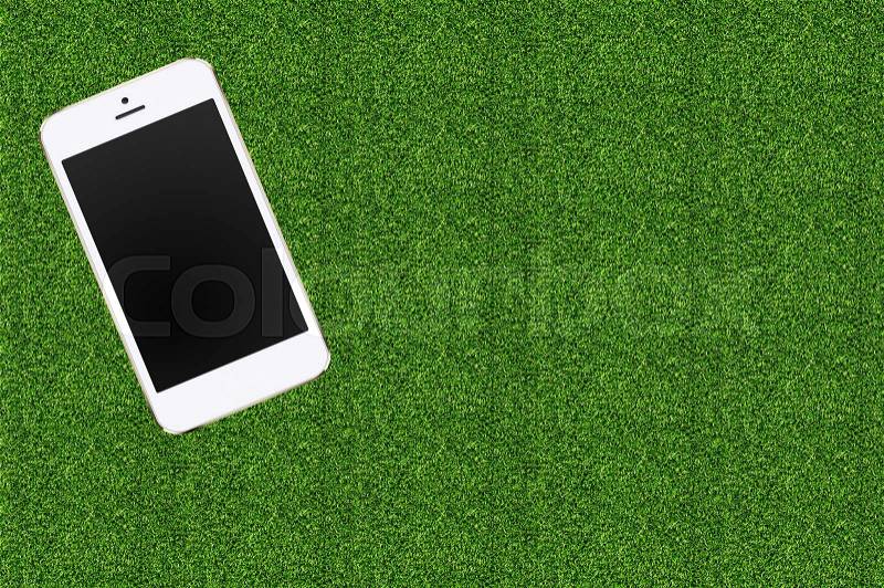 Mobile phone in the green grass, stock photo