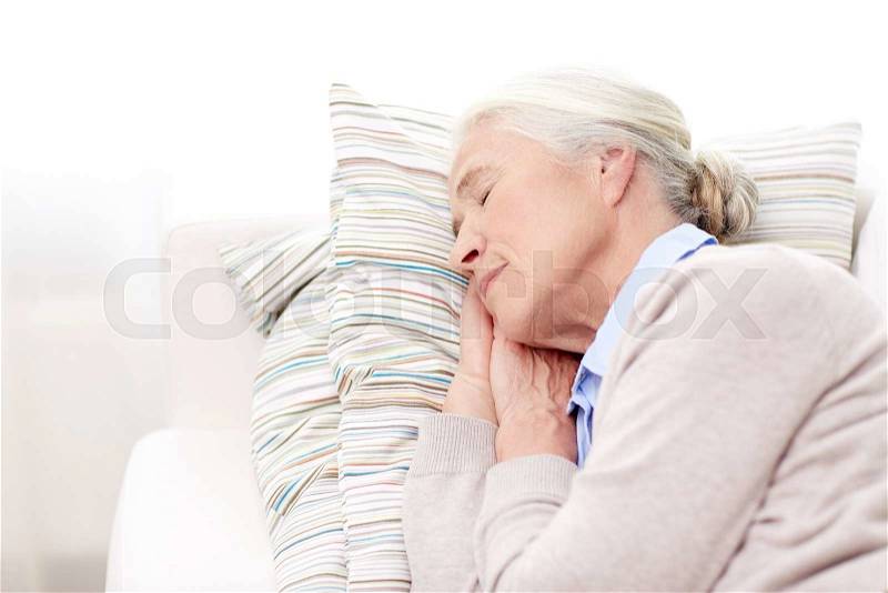 Age, relax and people concept - happy senior woman sleeping on pillow at home, stock photo