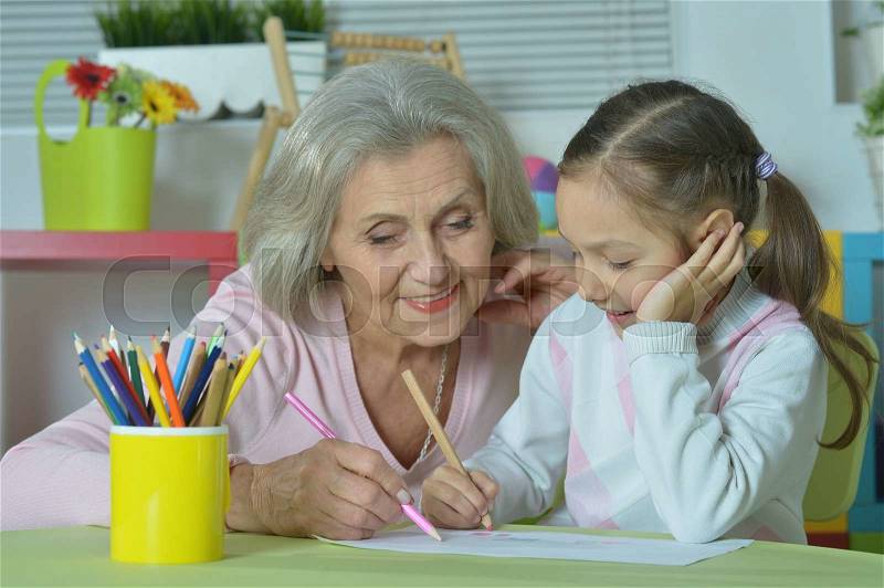 Portrait of a happy grandmother with granddaughter drawing together, stock photo
