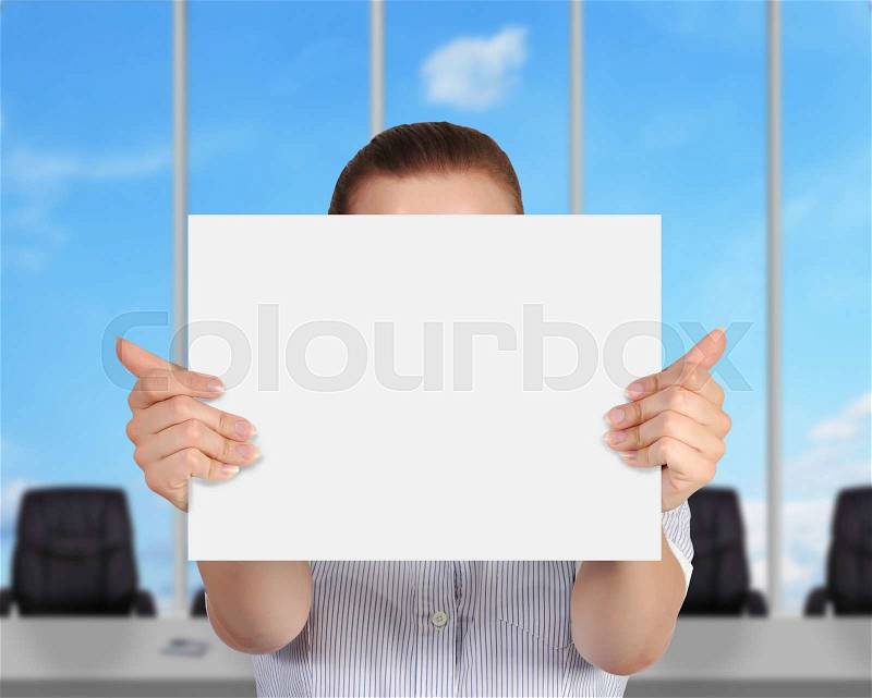 Businesswoman standing in modern office and showing blank paper, stock photo