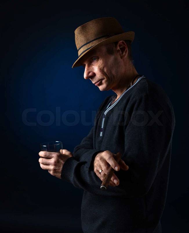 Man with hat smoking cigar, studio shot, stock photo