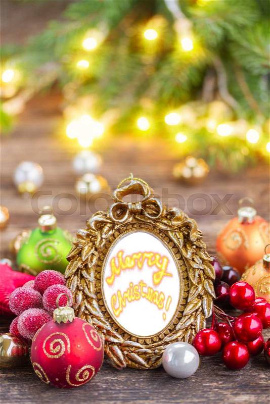 Christmas blank frame with merry christmas greetings sample text and decorations on wooden table with defocused lights and decorationd, stock photo