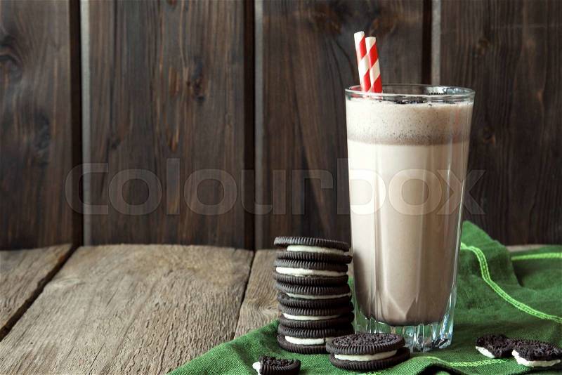 Homemade milkshake (chocolate smoothie) with cookies on rustic wooden table with copy space, stock photo