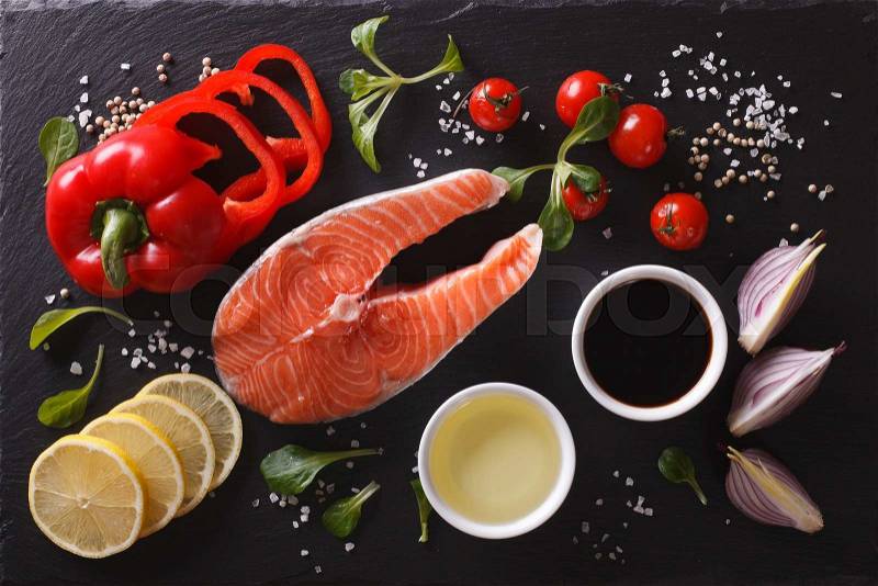 Raw salmon steak and ingredients on a black chopping board. Horizontal top view , stock photo