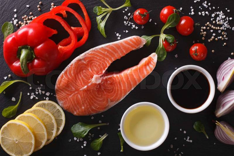 Raw salmon steak and ingredients on a black chopping board close-up. Horizontal top view , stock photo