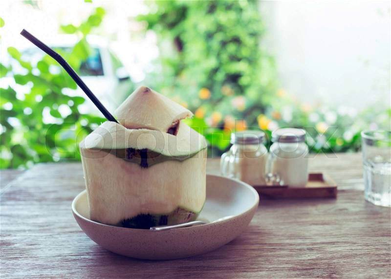 Fresh coconut water drink on wooden table with natural blur background, stock photo