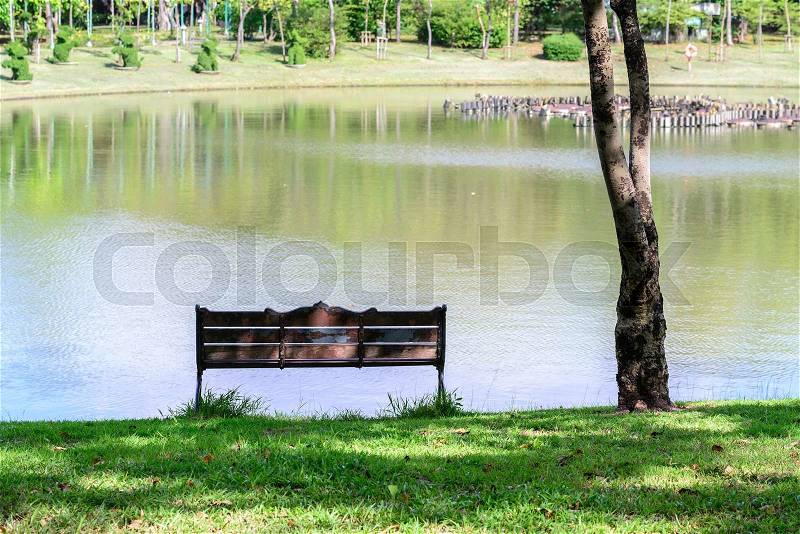 Vintage metal bench near pond in garden. , stock photo