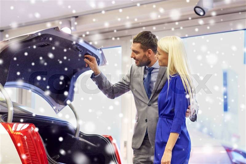 Auto business, car sale, technology and people concept - happy couple with car dealer in auto show or salon over snow effect, stock photo
