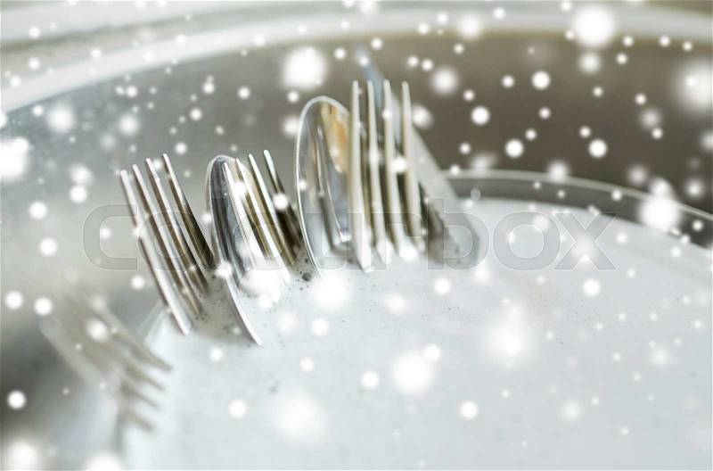 Housework, washing-up and housekeeping concept - close up of dirty dishes washing in kitchen sink over snow effect, stock photo