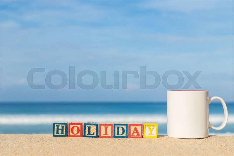 Word HOLIDAY in colorful alphabet blocks and coffee cup on tropical beach, Phuket Thailand, stock photo