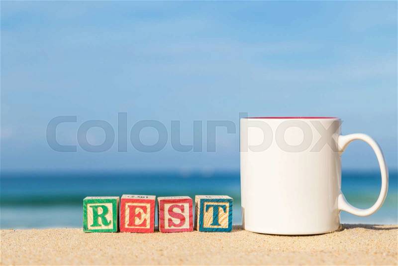 Word REST in colorful alphabet blocks and coffee cup on tropical beach, Phuket Thailand, stock photo
