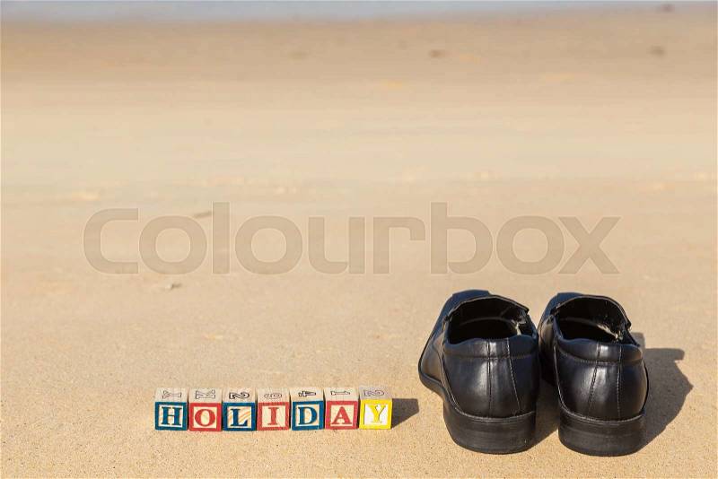 Word HOLIDAY in colorful alphabet blocks and black shoe on tropical beach, Phuket Thailand, stock photo